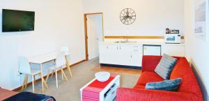 een woonkamer met een rode bank en een tafel bij The Esplanade Motel & Conference Centre in Palmerston North