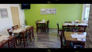 a restaurant with green walls and wooden tables and chairs at Hotel Mörike in Ludwigsburg