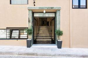 eine offene Tür zu einem rosafarbenen Gebäude mit Treppe in der Unterkunft Greece U Around Athens Thissio Suites in Athen
