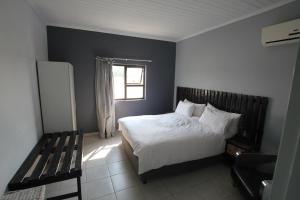 a bedroom with a bed and a window and a bench at Villa Graf in Ongwediva