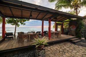 een houten terras met tafels en stoelen op het strand bij Amed Lodge by Sudamala Resorts in Amed