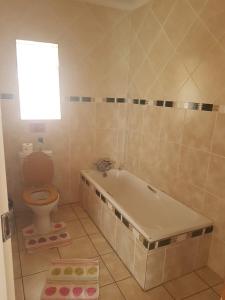 a bathroom with a tub and a toilet and a window at Queens Villa Guest House in Zeerust