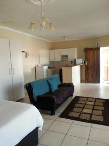 a living room with a couch and a kitchen at Queens Villa Guest House in Zeerust