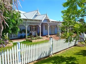 a white picket fence in front of a white house at Lanterns Retreats in Dunsborough
