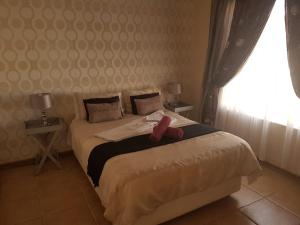 a bedroom with a bed with a pink ribbon on it at Queens Villa Guest House in Zeerust