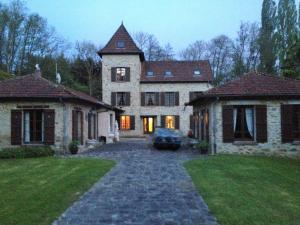 een groot stenen huis met een oprit in de tuin bij Le moulin régnelot - Chambre d'hôtes in Verdelot