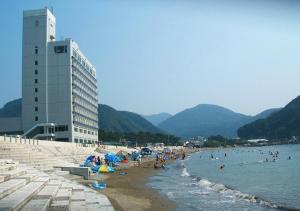 un gruppo di persone su una spiaggia con un edificio di Nishiizu Matsuzaki Itoen Hotel a Matsuzaki