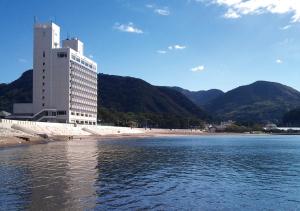 松崎町西伊豆松崎伊藤园酒店的海滩上的一座建筑,靠近一片水域