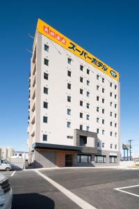 a large white building with a sign on top of it at Super Hotel Fukushima Iwaki in Iwaki