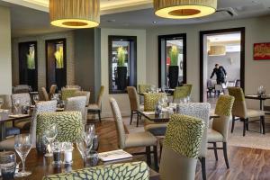 restauracja ze stołami i krzesłami oraz osobami w tle w obiekcie Best Western Plus Pinewood Manchester Airport-Wilmslow Hotel w mieście Handforth