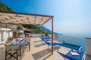 een patio met blauwe stoelen en tafels en uitzicht op de oceaan bij Casa Mare in Praiano