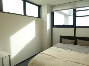 1 dormitorio con 1 cama y 2 ventanas en Nagoya Motoyama House A, en Nagoya