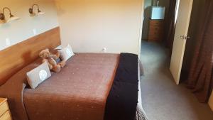 a bedroom with a bed with a teddy bear on it at Carmel Farmstay in Piopio