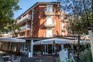 a building with tables and umbrellas in front of it at Hotel Orsa Maggiore in Milano Marittima
