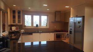 a kitchen with white cabinets and a stainless steel refrigerator at Carmel Farmstay in Piopio +12 photos
