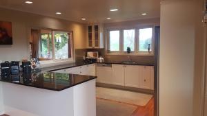 a kitchen with white cabinets and a black counter top at Carmel Farmstay in Piopio