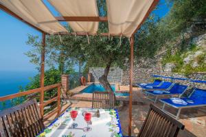 een patio met een tafel en stoelen en uitzicht op de oceaan bij Villa Tranquillita in Praiano