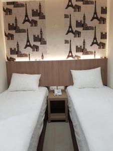 twee bedden in een kamer met een tafel ertussen bij Ethan Hotel Kelapa Gading in Jakarta