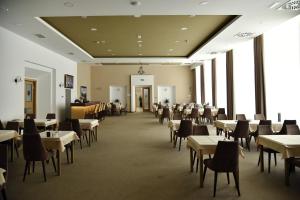 a dining room with tables and chairs and windows at Miznah Hotels & Resorts in Bačka Topola