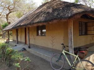 a bike parked in front of a house with a thatch roof at Tiko Community Centre in Saint Francis