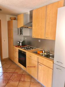 a kitchen with wooden cabinets and a sink at Residenz Moselzauber - Ferienwohnungen mit Pool Landschaft in Ernst