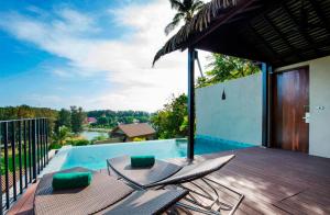 a deck with chairs next to a swimming pool at Sunsuri Phuket - SHA Plus in Nai Harn Beach