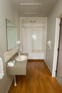 a bathroom with a sink and a mirror and a tub at Aspen Manor Motel in Hamilton