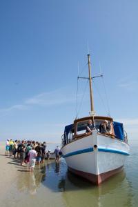 a group of people standing around a boat on the beach at Kleine Auszeit Pellworm in Pellworm