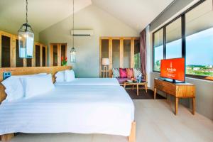 a bedroom with a large white bed and a tv at Sunsuri Phuket - SHA Plus in Nai Harn Beach