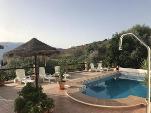 a swimming pool with chairs and an umbrella at Jardin Andaluz veleta in Pinos del Valle