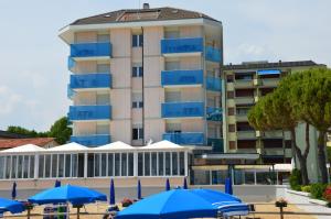 un edificio con sombrillas azules delante de él en Hotel La Bussola, en Lido di Jesolo