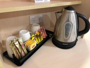 a tea kettle on a counter next to a tray of snacks at Adelaide Airport Motel in Adelaide