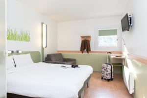 a hotel room with two beds and a chair at Hotel ibis budget Aix Les Bains - Grésy in Grésy-sur-Aix