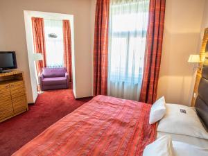 una camera d'albergo con un grande letto e una TV di EA Hotel Sonata a Praga