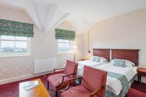 プリマスにあるDuke Of Cornwall Hotelのベッド1台と椅子2脚が備わるホテルルームです。