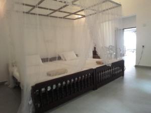 1 dormitorio con cama con dosel y cortinas blancas en Thusara Guesthouse en Mirissa