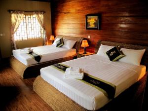 two beds in a hotel room with wooden walls at Atmaland Resort in Kep