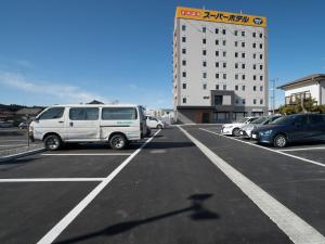 un estacionamiento con autos estacionados frente a un edificio en Super Hotel Fukushima Iwaki en Iwaki