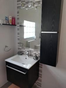 ein Bad mit einem Waschbecken und einem Spiegel in der Unterkunft Studio apartment with private terrace, Jacuzzi & views in Mosta