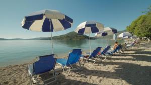 una fila de sillas y sombrillas en una playa en Avra Beach Hotel, en Nydri