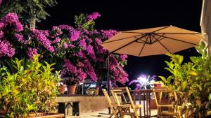 un patio con sillas, sombrilla y flores en La Grande Bellezza Trulli, en Martina Franca