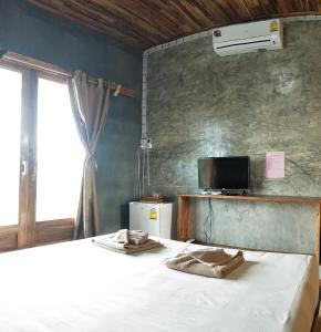 a bedroom with a bed and a tv and a window at Teak villa in Thoeng