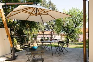 eine Terrasse mit einem Sonnenschirm, Tischen und Stühlen in der Unterkunft BB CÀ DE MÂ in Pietra Ligure
