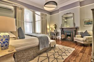 a bedroom with a bed and a fireplace and a mirror at Parker Cottage Guesthouse in Cape Town