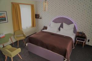 a bedroom with a bed and a table and a chair at Themenhotel 50's Ville Motel in Chemnitz