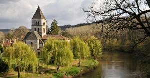 an old church next to a river with trees at Cottage Poppy in Tursac