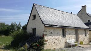 a white building with a gray roof and a bench at Le petit paradis in Daumeray