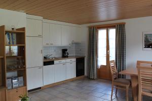 a kitchen with white cabinets and a wooden ceiling at Chalet Asterix in Grindelwald