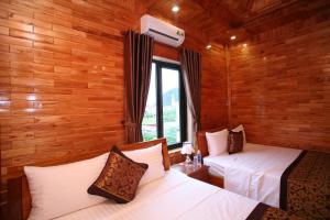 two beds in a room with wooden walls at Sky Hotel in Phong Nha