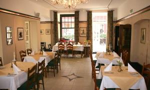 un ristorante con tavoli e sedie bianchi e un lampadario di Mutter Siepe a Lüdinghausen